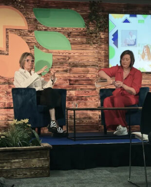 Two female speakers sitting on chairs on a stage giving a talk